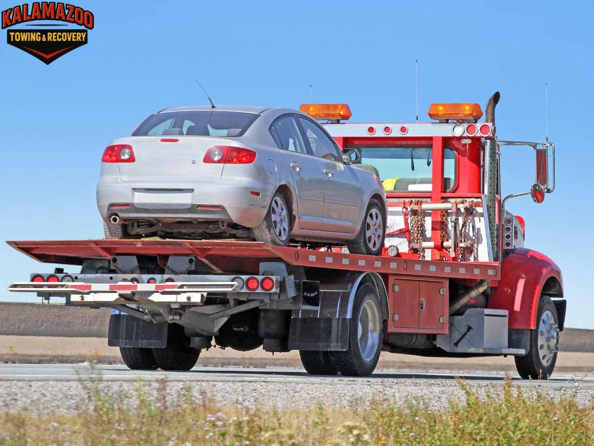 Kalamazoo tow truck assisting stranded car on I-94 shoulder at night