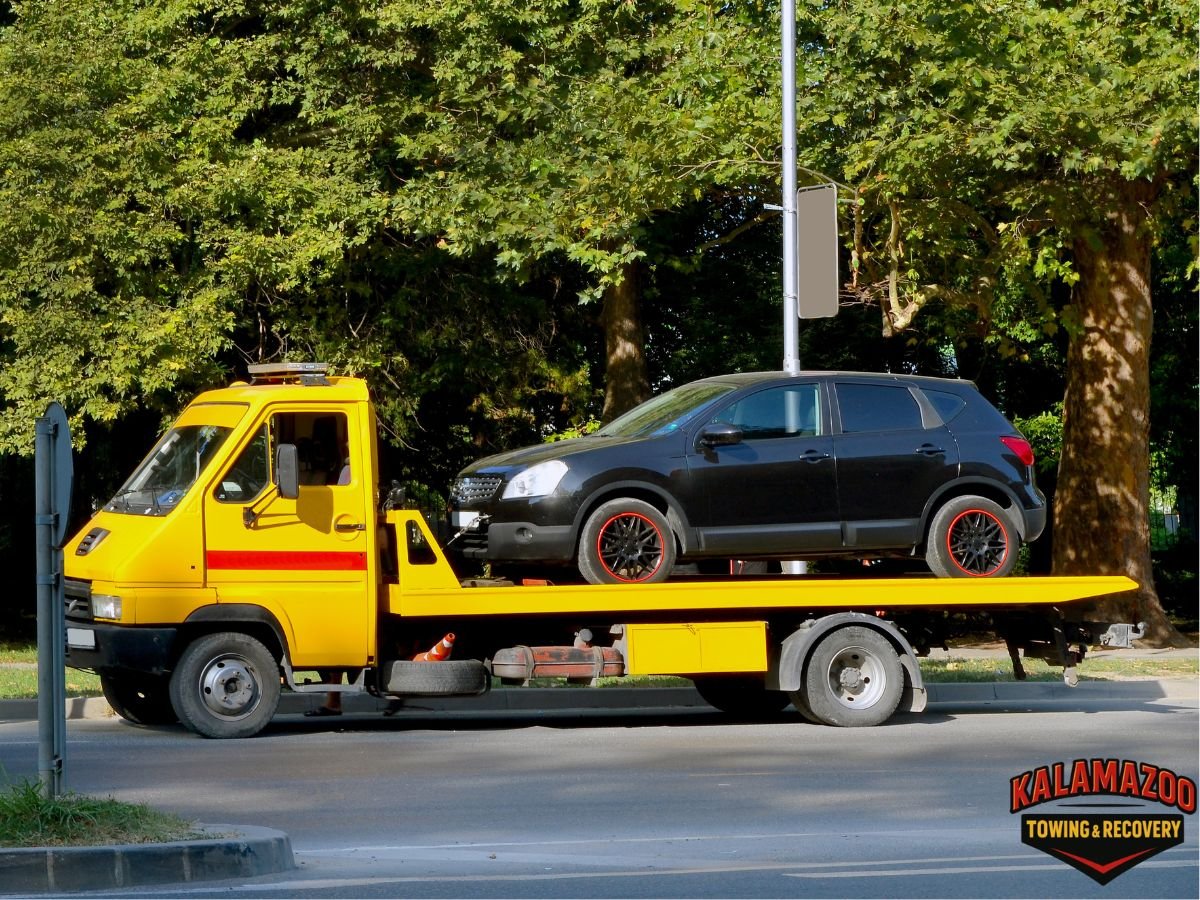 Tow truck assisting car on narrow neighborhood street in Kalamazoo MI